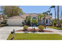 Charming single-story home featuring lush landscaping, a tile roof, and an attached two car garage at 10408 Double Bayou Way, Tampa, FL 33615