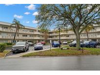Exterior view of the building with parking lot and mature trees, featuring multiple levels and a serene setting at 2379 Finlandia Ln # 21, Clearwater, FL 33763