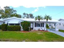Charming single-story home with a white exterior, well-manicured lawn, and mature landscaping featuring palm trees at 4517 100Th N Ave, Pinellas Park, FL 33782