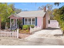 Charming pink home with white picket fence and lush landscaping creates an inviting curb appeal at 1874 N Washington Ave, Clearwater, FL 33755