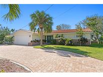 Charming single-story home with well-maintained landscaping and a brick-paved driveway, all under a bright blue sky at 222 Mar St, St Pete Beach, FL 33706