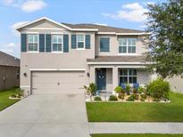 Charming two-story home featuring manicured landscaping, a two-car garage, and a cozy front porch at 11617 Miracle Mile Dr, Riverview, FL 33578