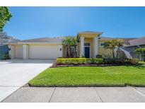 Inviting one-story home featuring a well-manicured lawn and two-car garage at 12406 Bristol Commons Cir, Tampa, FL 33626