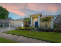 Charming single-story home with a well-manicured lawn, vibrant landscaping, and a two-car garage at 12406 Bristol Commons Cir, Tampa, FL 33626