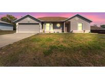 Charming single-story home featuring a manicured lawn and attached two-car garage at dusk at 13191 Siam Dr, Spring Hill, FL 34609
