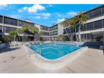 Relaxing community pool surrounded by lush landscaping at this condo complex with lounge chairs at 215 Valencia Blvd # 205, Belleair Bluffs, FL 33770