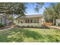 Charming single-story home featuring a well-manicured lawn, lush landscaping, and inviting covered front porch at 235 Aberdeen St, Dunedin, FL 34698