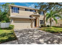 Two story home featuring a two car garage, neutral paint, dark shutters, landscaped yard and mature trees at 4821 Barchetta Dr, Land O Lakes, FL 34639