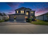 Beautiful two-story home featuring a three-car garage, stone accents, and manicured landscaping at 4904 Eagle Rock Dr, Wimauma, FL 33598