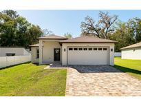 Charming single-story home featuring a brick-paved driveway, manicured lawn, and a two-car garage at 818 S Main St, Brooksville, FL 34601