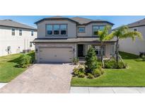 Charming two-story home with a paver driveway, two car garage and well manicured lawn with small palm trees at 10934 Sundrift Dr, Tampa, FL 33647
