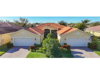 Beautiful single-story home with a well-manicured lawn, lush landscaping, brick driveway, and two-car garage at 16145 Amethyst Key Dr, Wimauma, FL 33598