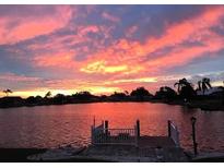 Beautiful water view from the house featuring a dock and a fiery sunset backdrop at 1710 New Bedford Dr, Sun City Center, FL 33573