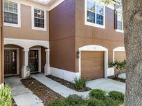 Townhome featuring a front door entrance with white pillars, landscaping, and an attached garage at 4910 Pond Ridge Dr, Riverview, FL 33578