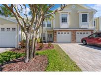 Charming townhome featuring a brick-accented facade, a paver driveway, and mature landscaping in the front yard at 914 Woodbridge Ct, Safety Harbor, FL 34695