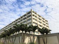 Low angle shot of a multi-story building framed by palm trees against a partly cloudy sky at 100 Bluff View Dr # 417A, Belleair Bluffs, FL 33770