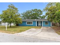 Charming single-story home featuring a blue exterior, well-manicured lawn and a concrete driveway at 1863 Alberta Dr, Largo, FL 33756