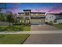 Elegant two-story home featuring a three-car garage, lush landscaping, and a paver driveway at 2911 Silva Wood Dr, Valrico, FL 33596