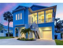 Beautiful blue two-story home on stilts featuring a large porch and well-manicured landscaping at 720 Bay Esplanade, Clearwater Beach, FL 33767