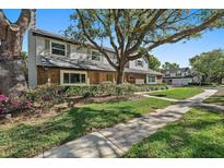Charming two-story home featuring brick and vinyl siding, mature landscaping, and a beautiful lawn at 9067 Cypress Trl, Seminole, FL 33777