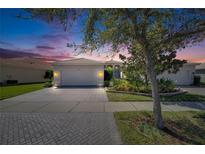 Charming single Gathering home with tile roof, landscaping, brick driveway, and two car garage at 15657 Aurora Lake Cir, Wimauma, FL 33598