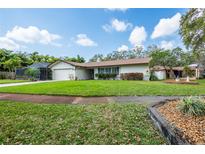 Well-maintained single-story home features a lush lawn, mature trees, and a screened-in lanai at 1830 Oak Forest S Dr, Clearwater, FL 33759