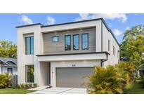 Modern two-story home featuring clean lines, a gray garage door, and tropical landscaping at 2519 N Riverside Dr, Tampa, FL 33602