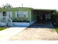 Charming single-story home featuring a covered carport, landscaped flower beds, and a cozy front porch with white railings at 36624 Kay Ave, Zephyrhills, FL 33542
