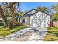 Charming home features a two-car garage, beautifully landscaped front yard, and a welcoming front porch at 9310 N Willow Ave, Tampa, FL 33612