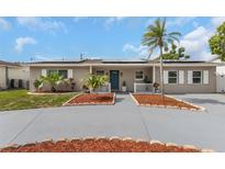 Charming single-story home with solar panels, manicured landscaping, and a vibrant blue front door at 13414 Alpine Ave, Seminole, FL 33776