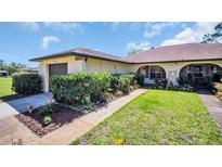 Charming single-story home with a well-manicured lawn and colorful, mature landscaping at 3479 Maclaren Dr, Palm Harbor, FL 34684