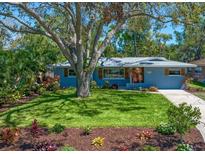 Charming single-story home featuring a lush front lawn, colorful landscaping, and a beautiful shade tree at 1220 Parkview Ln, Largo, FL 33770