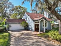Charming home featuring a brick driveway, attached garage, and an arched entryway with white columns at 14910 Northwood Village Ln, Tampa, FL 33613