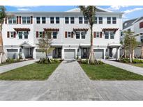 Attractive row of three-story townhomes with grey garages, tasteful landscaping, and tree-lined walkway at 1623 Sea Haven Dr # 307, Punta Gorda, FL 33950