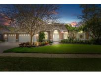 Beautiful single-story home with a brick facade, three-car garage and well-manicured lawn at 17807 Crystal Cove Pl, Lutz, FL 33548