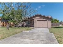 Tan single-Gathering home with an attached garage and a concrete driveway, showcasing its traditional design and landscaping at 2401 16Th N Ave, St Petersburg, FL 33713