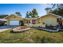 Charming single-story home with a well-maintained lawn, vibrant landscaping, and unique decorative fountain at 3531 Glossy Ibis Ct, Palm Harbor, FL 34683