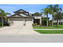 Stunning two-story home featuring a three-car garage and lush tropical landscaping at 5006 Ivory Stone Dr, Wimauma, FL 33598