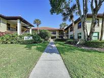 Beautiful condominium building with mature landscaping, sidewalks and palm trees at 513 Hammock Pine Blvd, Clearwater, FL 33761
