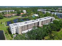 Aerial view of a low-rise condo complex surrounded by lakes, lush trees, and other buildings at 5920 80Th N St # 107, St Petersburg, FL 33709