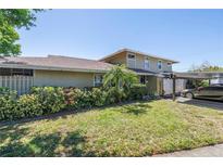 Charming home exterior with a lush, landscaped front yard and convenient carport at 6902 El Centro Ct, Tampa, FL 33634
