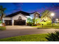 Charming two-story home boasting lush landscaping and a spacious three-car garage at twilight at 6927 Crestpoint Dr, Apollo Beach, FL 33572