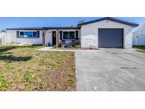 Charming single Gathering home featuring updated brickwork, neutral paint, dark shutters, and a grey garage door at 1182 Fernwood Dr, Holiday, FL 34690