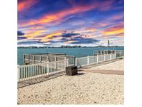 Waterfront backyard featuring a private dock, white picket fence, and beautiful sunset views at 1445 Corey S Way, South Pasadena, FL 33707