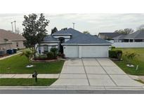 Charming home featuring a well-maintained lawn and a spacious three-car garage with a concrete driveway at 3215 Coconut Grove Rd, Land O Lakes, FL 34639