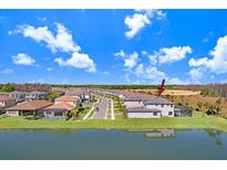 Aerial view showcasing the rear of a home with a screened-in patio and water view in a suburban neighborhood at 32423 Rosewood Meadow Ln, Wesley Chapel, FL 33543