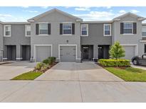 Exterior view of gray two-story townhome with front-entry garage and well-maintained landscaping at 33064 Tulip Petal Ln, Wesley Chapel, FL 33545