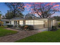 Charming single-story home with a brick pathway, manicured lawn, carport, and beautiful landscaping at 4630 W Bay Villa Ave, Tampa, FL 33611