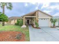 Charming home featuring stone accents, well-manicured lawn, and a welcoming entrance at 1232 Persimmon Dr, Holiday, FL 34691