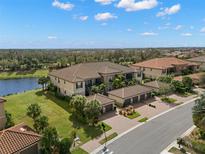 Beautiful aerial view of a modern condo complex with garages, lush landscaping and a scenic lake in the background at 13714 Messina Loop # 101, Bradenton, FL 34211